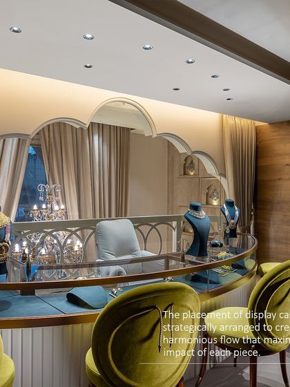 The placement of display cases is strategically arranged to create a harmonious flow and maximize the impact of each piece. This curved counter with olive green chairs offers a comfortable and elegant viewing area for customers.