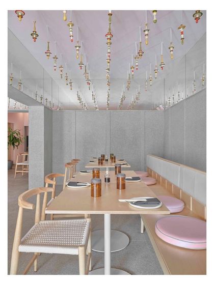 A closer view of the dining area beneath the Channapatna craft installation. The mirrored beams reflect the colorful modules, making the space feel open and creating an endless pattern of form and color.
