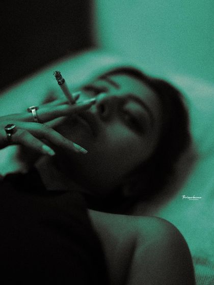 A dark and moody boudoir-style shot, using colored gels to create a dramatic, non-traditional look. The focus is on form and shadow.