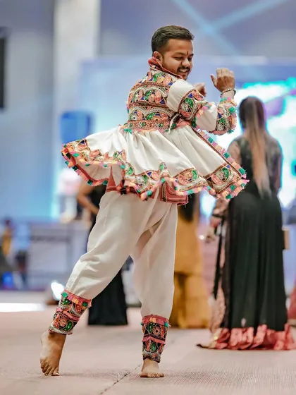 A male dancer is captured mid-twirl, his traditional white Garba outfit creating a beautiful circular motion.