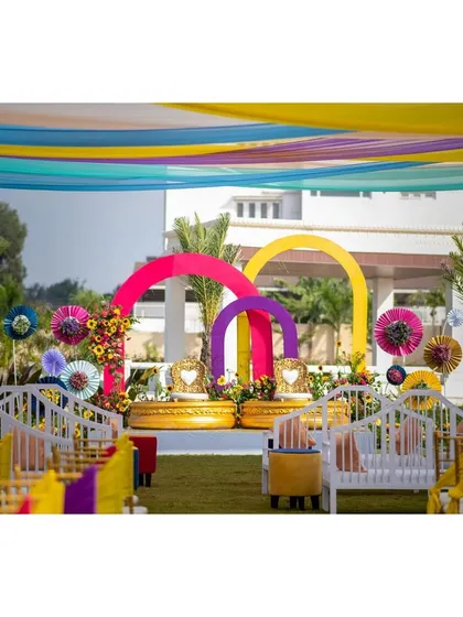 A wide shot of the Haldi venue, with colorful drapes creating a festive canopy over the entire lawn.