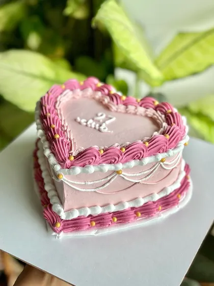 A full view of the two-tiered effect on this heart-shaped vintage cake, with intricate piping creating a beautiful, classic look for a 27th birthday.