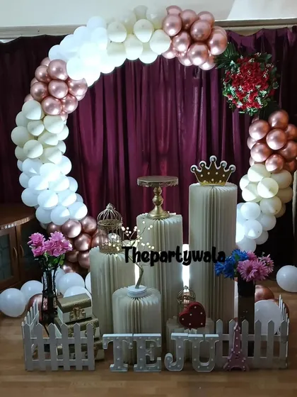 A beautiful ring decoration with rose gold and white balloons against a dark curtain. The contrast makes the colors pop.