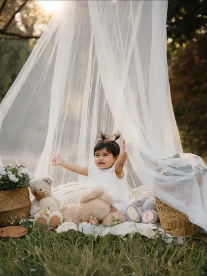 A toddler plays peek-a-boo with the sheer fabric of her teepee. These playful moments make for adorable outdoor kids' photos.