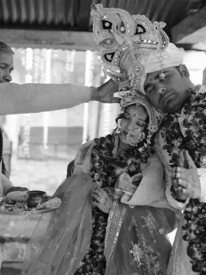 A black and white shot of a priest blessing the couple during their wedding ceremony, capturing the solemnity of the ritual.