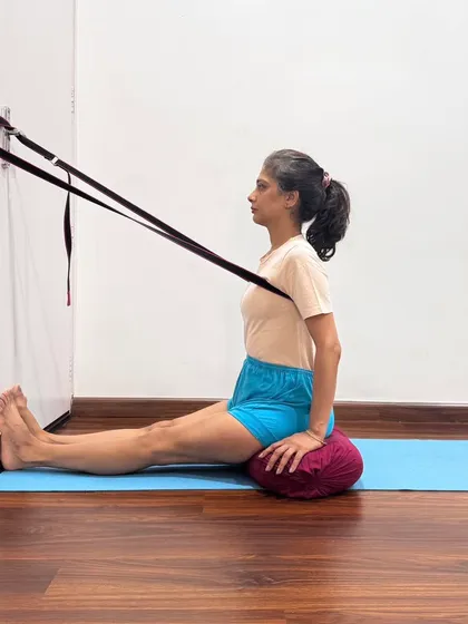 Using a wall belt in Dandasana provides traction to the upper back. This helps to lift the spine and open the chest, correcting posture and preparing the body for pranayama. It is a simple yet powerful way to understand spinal alignment.