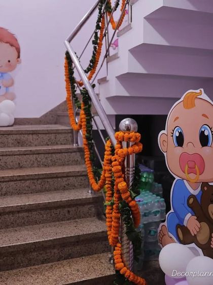 I love using staircases to continue the decor theme. Here, I placed cute baby cutouts and marigold garlands along the stairs for a baby shower celebration.