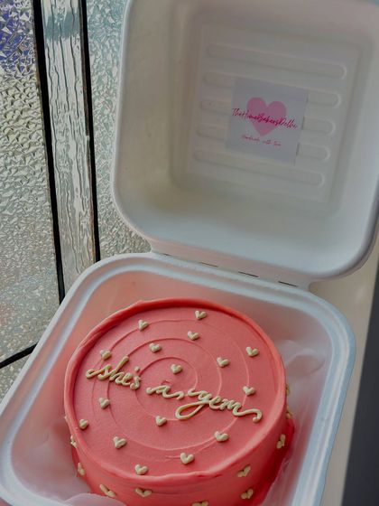 A beautiful coral-pink bento cake with the message 'she's a gem' in elegant gold script. Perfect for celebrating the amazing women in your life.
