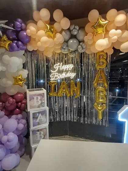 A similar "Baby" shower or first birthday setup, showing the 'BABY' blocks and marquee number '1' against a silver fringe curtain.