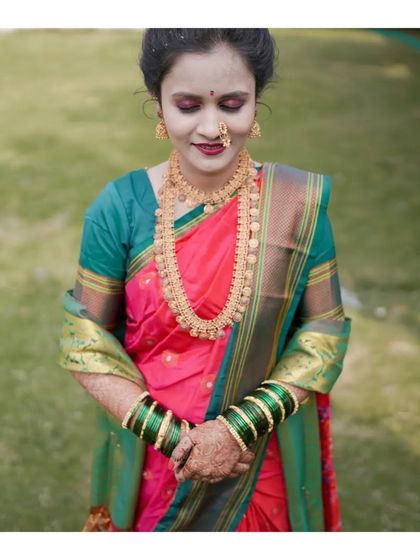 A medium shot of a model in a pink and green traditional saree. This pose highlights the intricate gold necklace and the overall grace of the ethnic attire.