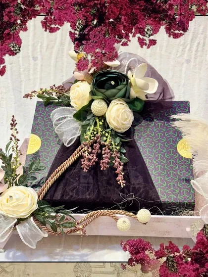 A beautifully decorated gift box, part of a larger trousseau. The floral and rope details on the tray add a rustic yet elegant charm.