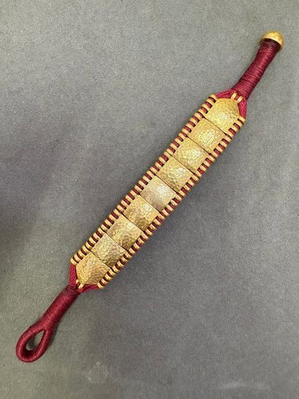 A close-up of the gold-plated version of our woven bracelet, showing the texture of the hammered squares.