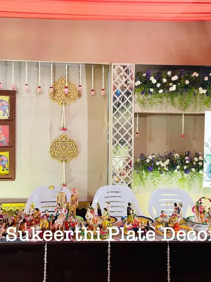 A very traditional and artistic setup for a wedding. The platters are arranged on a decorated table, featuring a variety of handmade dolls depicting cultural scenes.