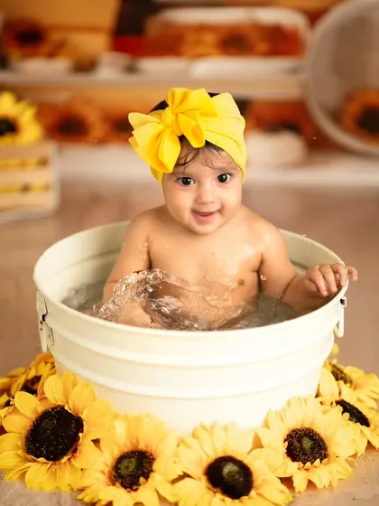 A happy baby enjoys a splash in a tub during our sunflower-themed milk bath session. These shoots are a fun and unique way to capture a milestone.