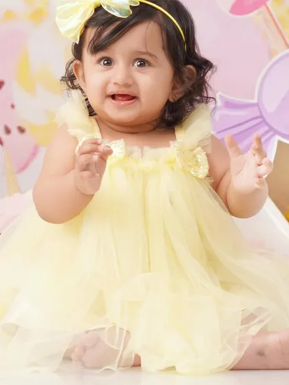An expressive portrait of the birthday girl clapping her hands with excitement in her colorful Candyland setting.