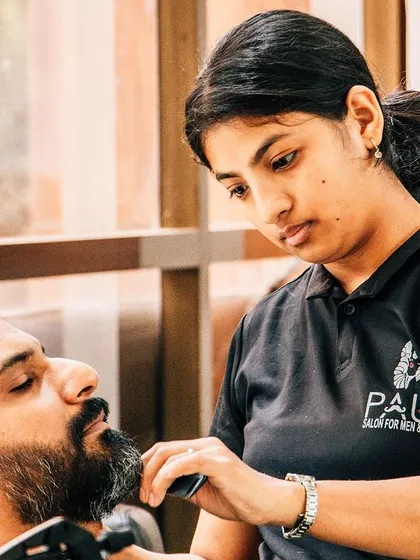 A sharp beard is just as important as a good haircut. Here, one of my expert stylists is carefully trimming and shaping a client's beard. I ensure we pay close attention to the lines and details for a clean, professional look.