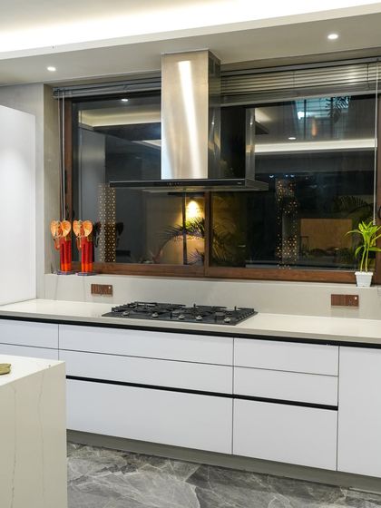 A shot of the hob and chimney in Prachi and Prashant Jain's Jamshedpur kitchen. The clean white drawers and countertop contrast with the stainless steel appliances for a timeless look.