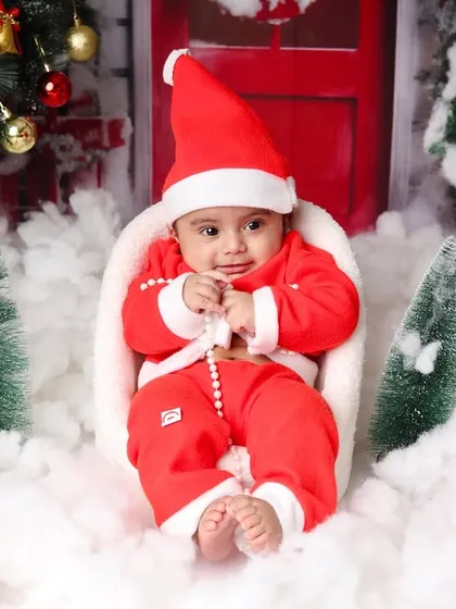 A cute shot of the baby Santa looking at his hands, sitting comfortably in the middle of the winter wonderland set.
