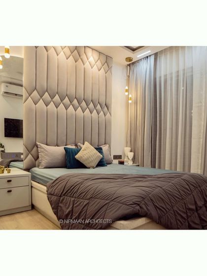 A master bedroom with a dramatic, full-height upholstered headboard. This feature adds a sense of luxury and comfort, making the bed the undeniable centerpiece of the room.