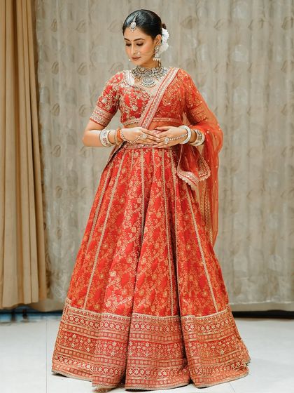 Another full-length shot of the red lehenga, showcasing its beautiful design and the bride's graceful pose.