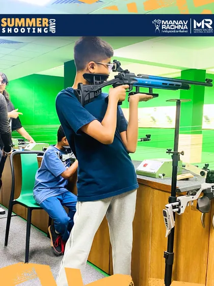 A young shooter focuses on his target during a summer camp session. We provide age-appropriate equipment and a supportive environment to help children develop their concentration and skills.