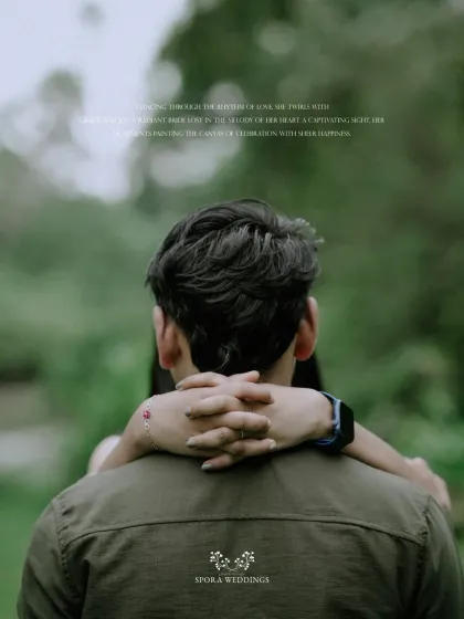 An intimate shot from behind the groom, with the bride's arms wrapped around him in a loving embrace.