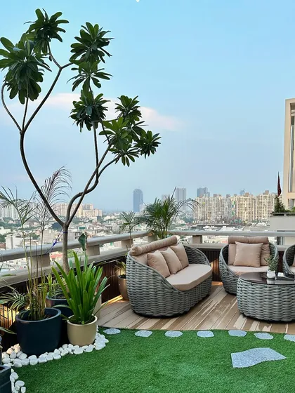 The complete seating arrangement on the rooftop terrace. The combination of a large tree, potted plants, and soft turf creates a garden-like feel high above the urban bustle.