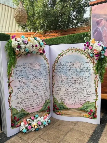 A truly unique photo opportunity: a giant, open storybook prop, adorned with flowers, perfect for a fairytale or Bridgerton-themed event.