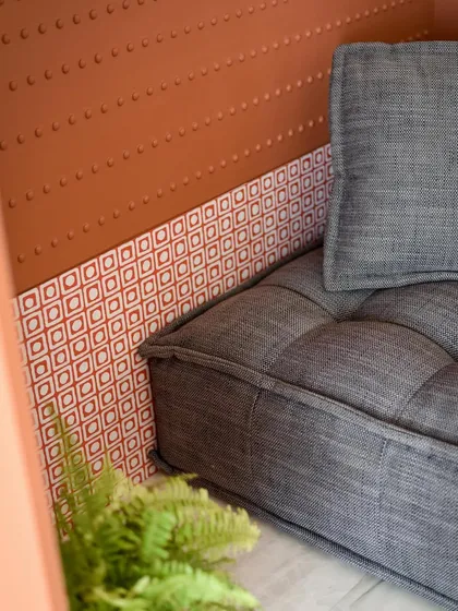 A close-up of the reading nook, showing the beautiful contrast between the textured grey fabric of the lounger and the patterned tiles at the base.