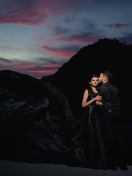 A dramatic silhouette against the twilight sky. The flowing black dress adds to the moodiness of the shot, creating a powerful and artistic image as night begins to fall.