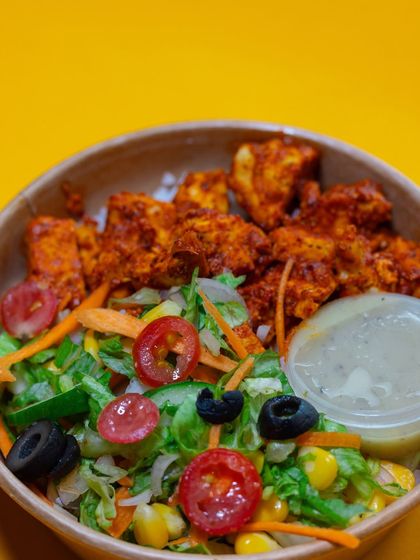 A closer look at the vibrant colors of our Chicken Tikka Meal. The red of the chicken, the green of the lettuce, and the black of the olives make for a truly appetizing and healthy dish.