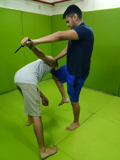 This drill focuses on disarming an attacker who is holding a knife. The technique involves controlling the weapon arm, applying a joint lock, and using a knee strike to break the opponent's posture and resolve. This is advanced, reality-based training.