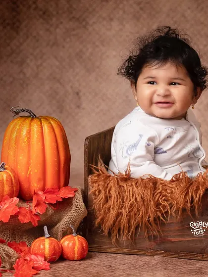 Autumn cuddles with our pumpkin bundle. A happy baby enjoys the cozy feeling of our fall-themed setup.