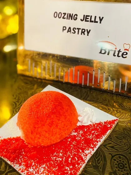 A close-up of the "Oozing Jelly Pastry," a unique dessert with a vibrant red coating and a surprise jelly center.