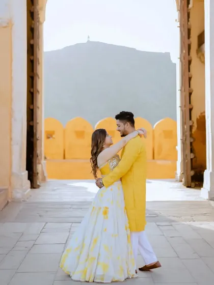 Framed by a grand palace gateway, this shot captures the couple against the backdrop of the Aravalli hills. It’s a perfect blend of architectural and natural beauty.
