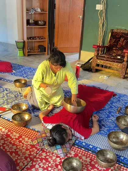 A close-up of a sound healing session, showing the placement of a large singing bowl on the back for deep vibrational therapy.