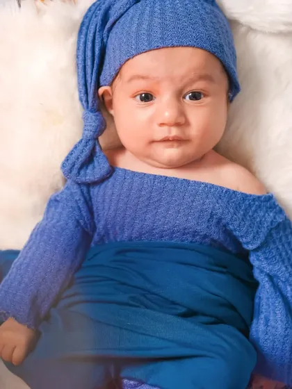 A close-up portrait of a newborn baby boy in a cozy blue outfit. These simple shots focus on their perfect, tiny features.