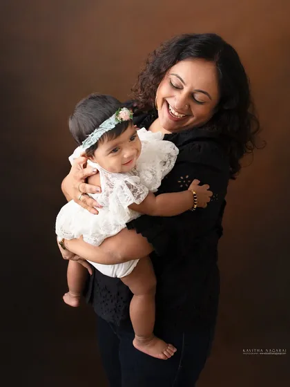 A mother and her eight-month-old daughter share a moment of pure joy. The baby's smile and the mother's laughter make this a truly heartwarming portrait.