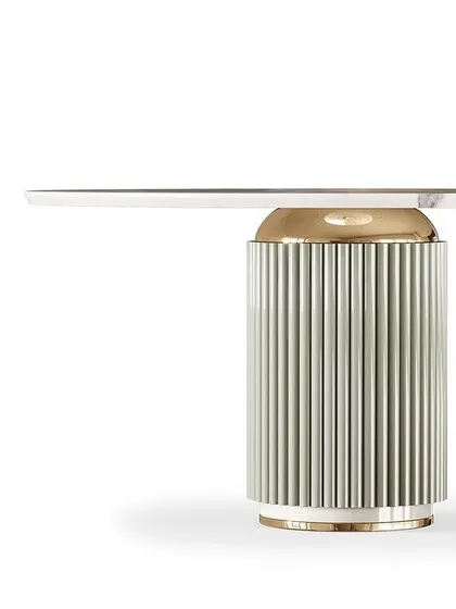 This dining table design features a fluted pedestal base in a soft white finish, accented with PVD gold. It's a six-seater, perfect for bringing family and friends together in style.