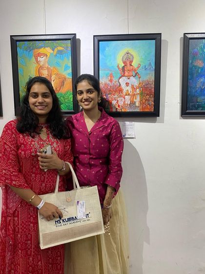 Two artists at the Chitrakar exhibition, one proudly holding a tote bag from the NS Kumbar Art Academy. We are a community of creators.