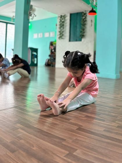 A young student in our Powerpuff Beginners class focuses intently on her toe touch stretch. We teach them to start building good flexibility habits early in a fun, encouraging way.