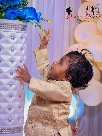 A curious little boy reaches up to touch the decorative flowers during his birthday shoot. It's these small, unscripted moments of discovery that make for the most memorable photos.