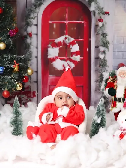 This little Santa sits in his chair, surrounded by a complete Christmas village scene with a tree, reindeer, and snowman.