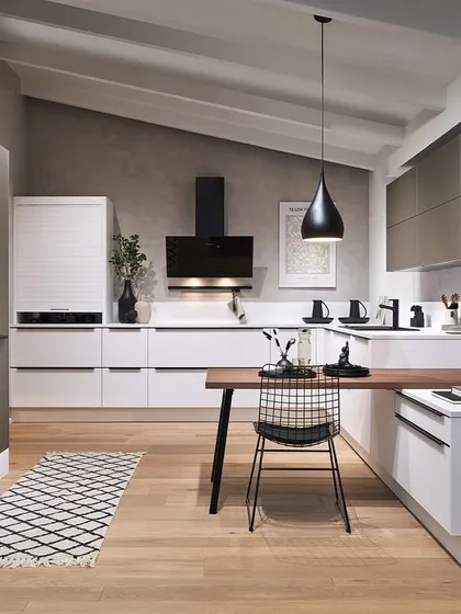 A novelty for 2025, this kitchen design features a mix of white and greige cabinets, with a wooden dining table extension creating a cozy, integrated eating area.
