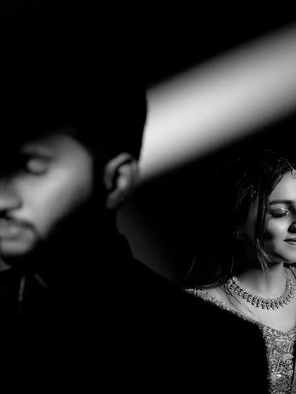 A dramatic black and white portrait using a sliver of light to illuminate the bride. The play of light and shadow creates a moody, artistic, and intimate feel.