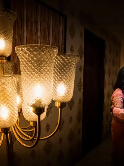 In the quiet corners, away from the crowd, are where the most intimate moments happen. The warm glow of the chandelier highlights a tender forehead kiss, a silent promise between the couple.