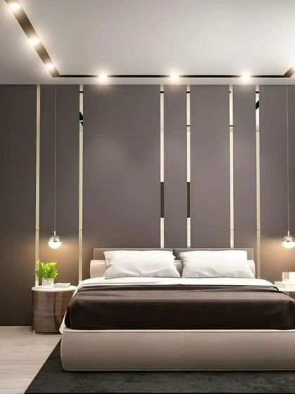 We designed this modern bedroom with a focus on clean lines and ambient lighting. The feature wall behind the bed has vertical metallic strips, and the false ceiling includes track lighting, creating a sleek and well-lit space.