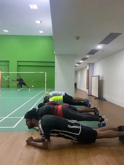 Core strength is the foundation of a powerful badminton player. Our adult shuttlers hold their planks, building stamina and stability while a match plays out in the background.
