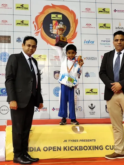 Young Azai stands on the first place podium, holding his trophy and gold medal high at the India Open Kickboxing Cup. We start building champions from their very first tournament.