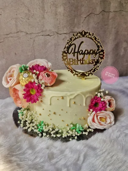 A beautiful blend of fresh flowers and sweet frosting. This simple yet elegant cake is adorned with a cascade of pink flowers and baby's breath, perfect for a lovely birthday celebration.